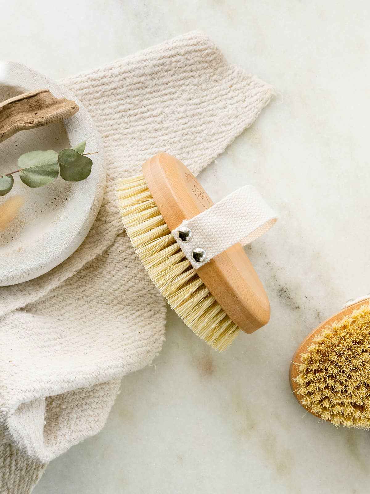 Oval dry brush with wood handle and yellow sisal bristle head, white fabric strap