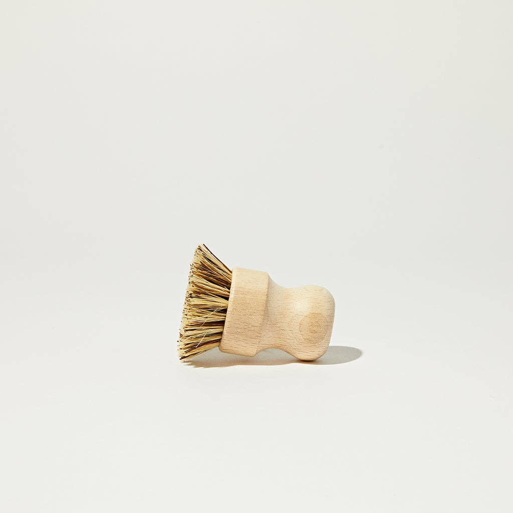 Angled wooden scrub brush with natural bristles and rounded handle.
