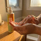 Dr. Watson's face wash bottle beside lathering hands