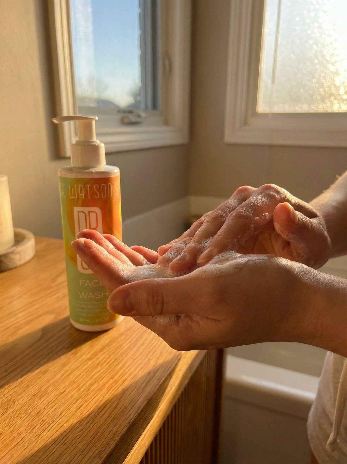 Dr. Watson's face wash bottle beside lathering hands