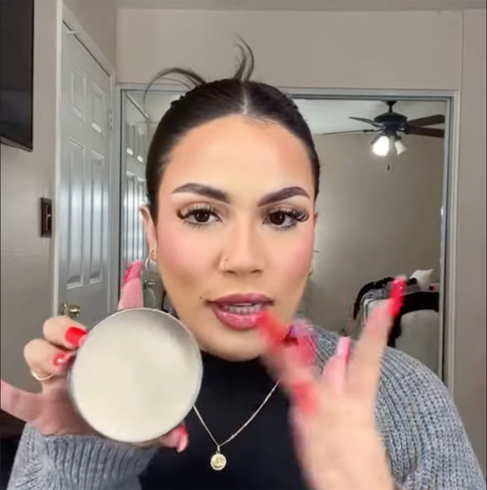 Person holding a pomade container and demonstrating how to use.