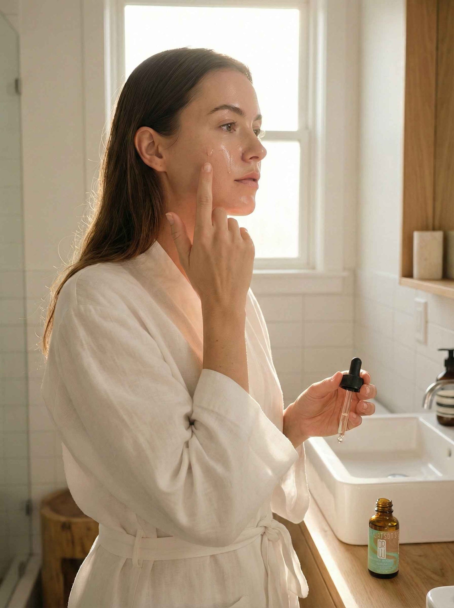 Woman applying Radiance Boosting serum, holding a small bottle with black dropper