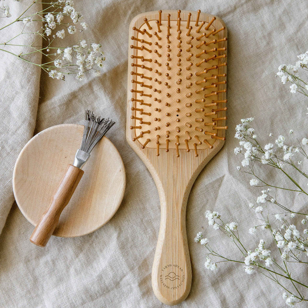 Bamboo hair brush with wooden paddle and bristle pins, oval cushion handle.
