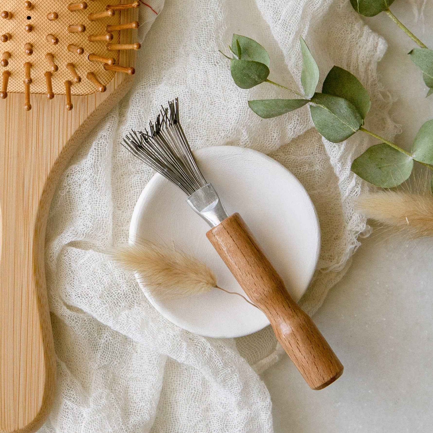 Bamboo hair brush detail with curved wooden handle and pin bristles in square pad