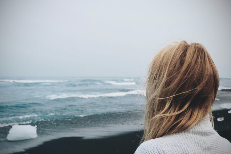 Woman overlooking waves at the beach.
