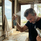 Sea salt spray bottle held near face with white trigger sprayer releasing mist