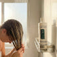 Dr. Watson's conditioner bottle on bathroom shelf, white with pump cap and green label
