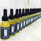 Row of hair oil bottles with black droppers, yellow oil, Dr Watsons labeling