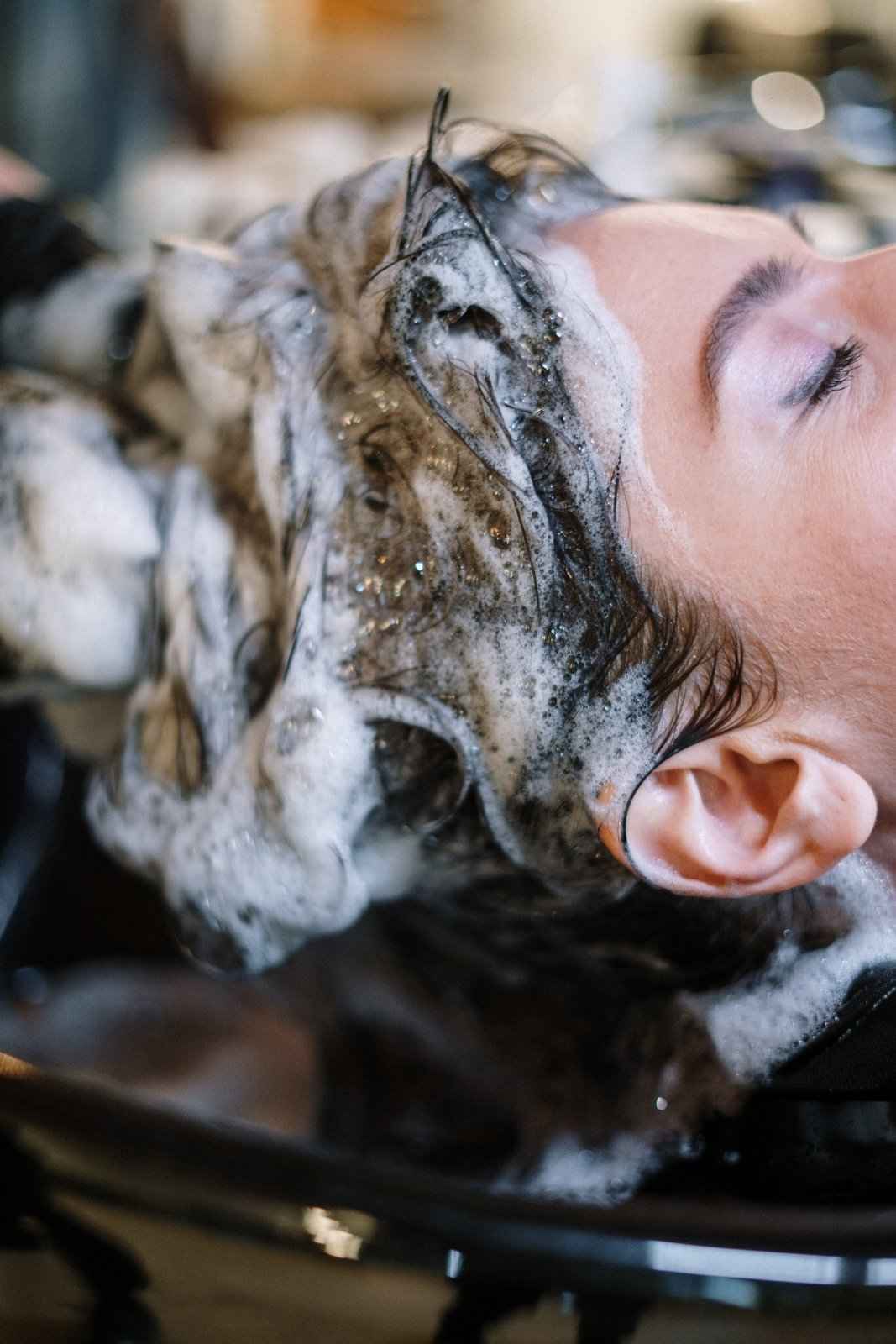 Shampoo foam on dark hair and scalp, face partially lathered